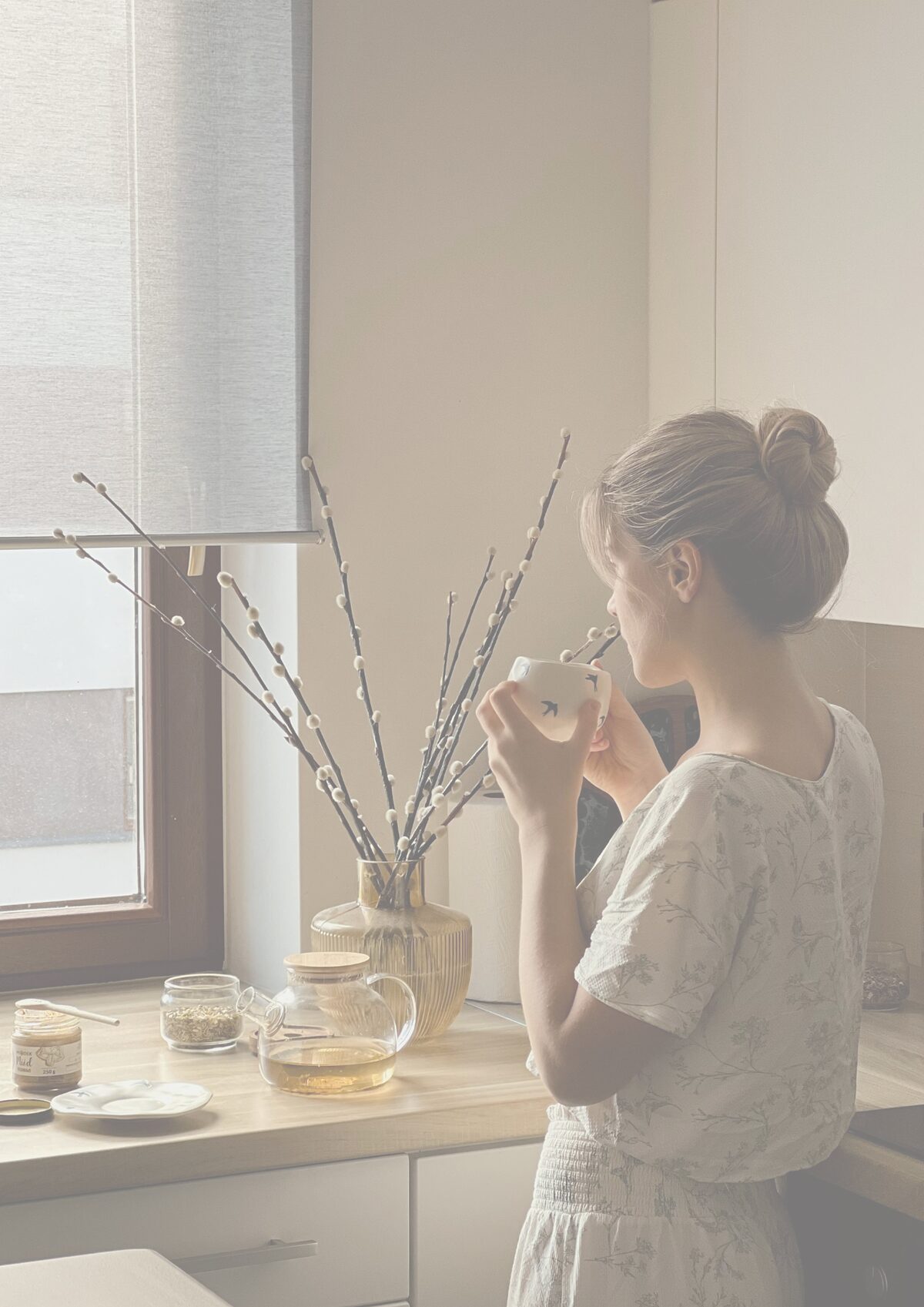 Mutter steht ruhig am Küchenfenster mit einer Tasse Tee – ein Moment für sich